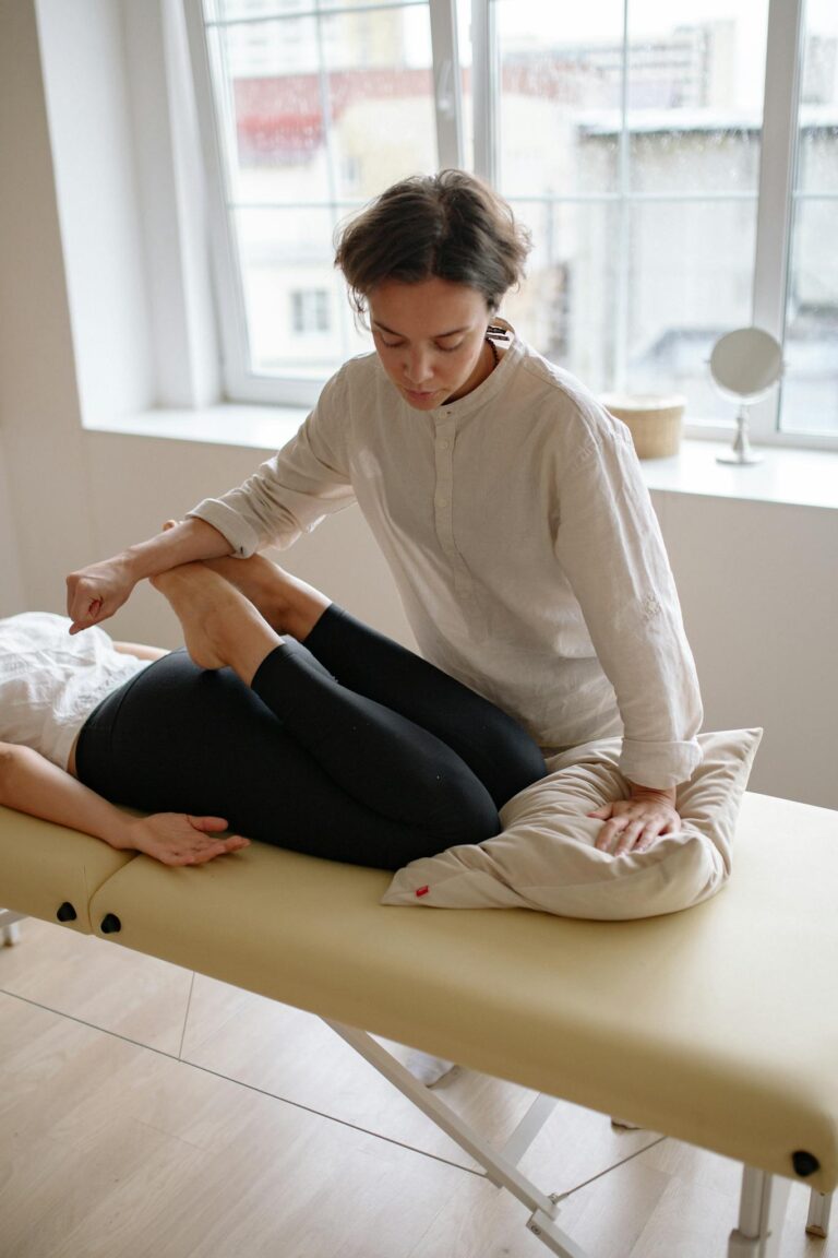 Massage therapist performing stretching techniques on a client indoors for relaxation and wellness.